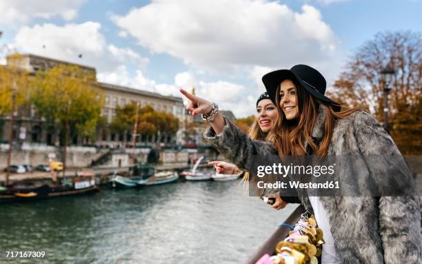 france, paris, two young women leaning on a bridge over the seine river - découverte photos et images de collection