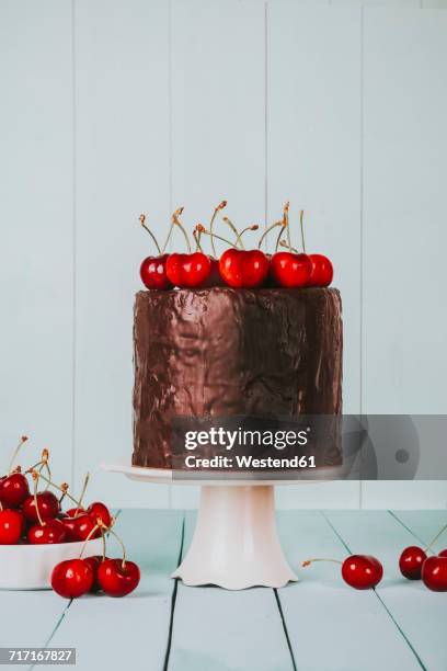 cake with chocolate icing and cherries on top on cake stand - chocoladeglazuur stockfoto's en -beelden