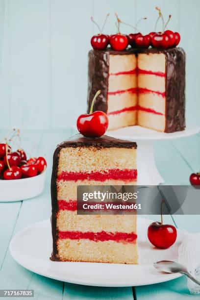 piece of cake with chocolate icing and cherries on plate - taartpunt stockfoto's en -beelden