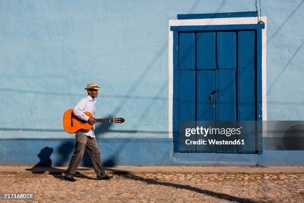 cuba, man with guitar walking on the street - street artist - fotografias e filmes do acervo