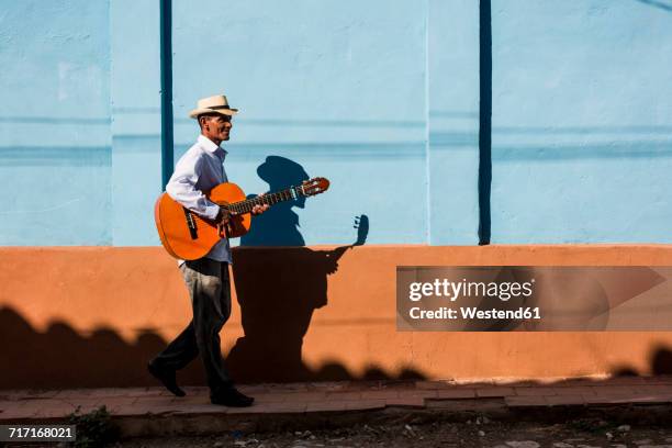 cuba, man with guitar walking on the street - street artist - fotografias e filmes do acervo