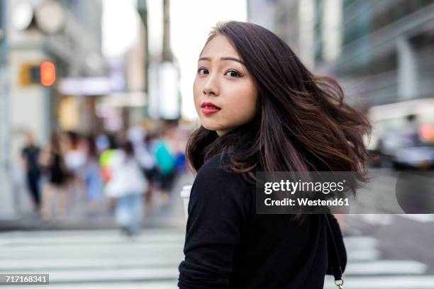 usa, new york city, manhattan, portrait of young woman looking over her shoulder while crossing street - asian hair stock-fotos und bilder