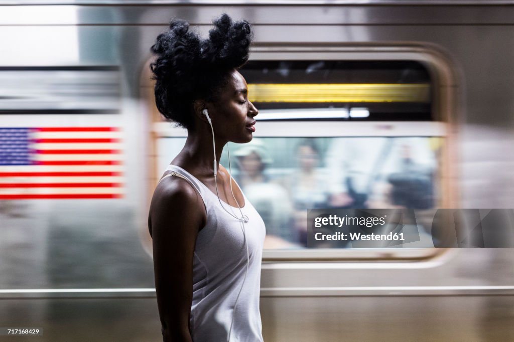 USA, New York City, Manhattan, woman with earphones on subway station platform