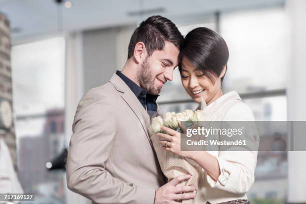 man handing over roses to woman at home - happy anniversary stock pictures, royalty-free photos & images