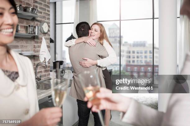 man and woman hugging in kitchen at a gathering - gift lounge stock pictures, royalty-free photos & images