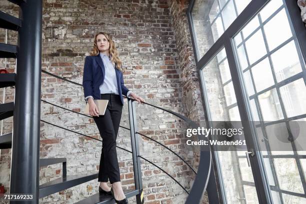 businesswoman walking down spiral staircase - businesswoman under stock-fotos und bilder
