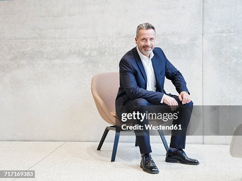 Portrait of smiling businesssman sitting in armchair Portrait of smiling businesssman sitting in armchair
