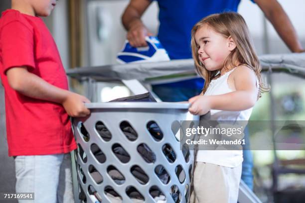 two children helping father with chores carrying laundry basket - man washing basket child stock pictures, royalty-free photos & images
