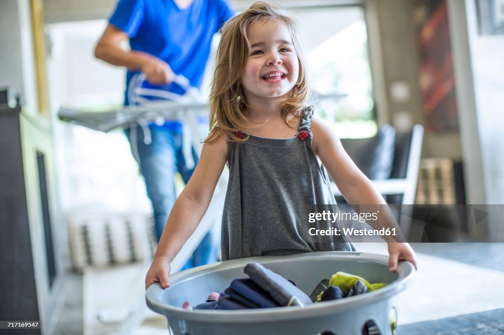 Happy baby girl holding laundry basket