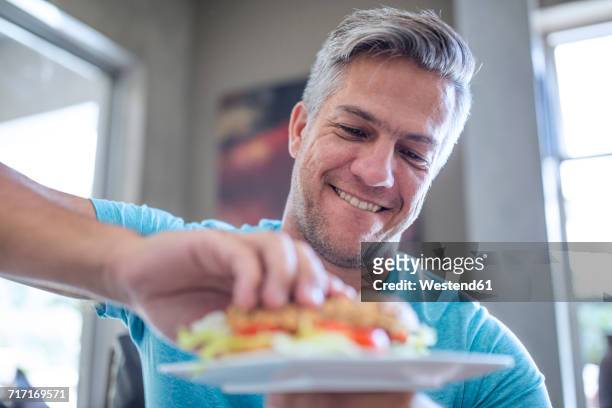 man having a sandwich from plate - geniessen teller essen stock-fotos und bilder