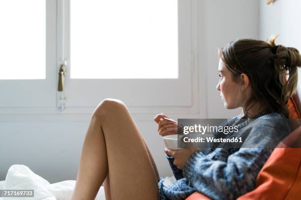 serious young woman eating cereals in bed - woman eating stockfoto's en -beelden