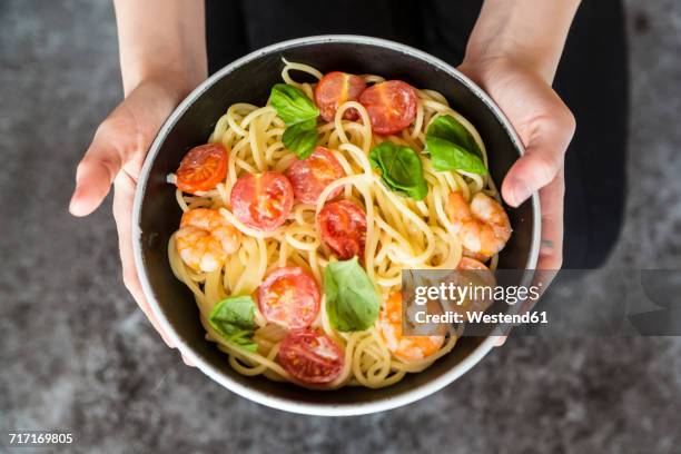 hands holding bowl of spaghetti with prawns, tomatoes and basil - 盛り付け 手 ストックフォトと画像