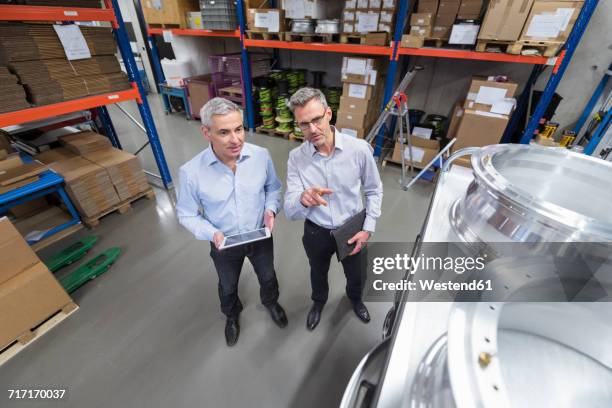 two businessmen in factory hall talking - weitwinkel stock-fotos und bilder