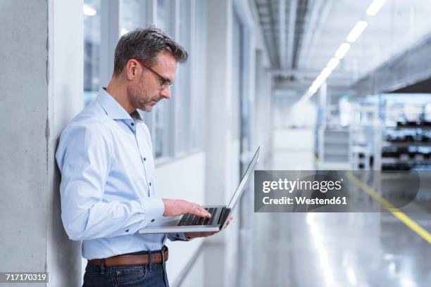 manager on shop floor of factory using laptop - halle stock-fotos und bilder