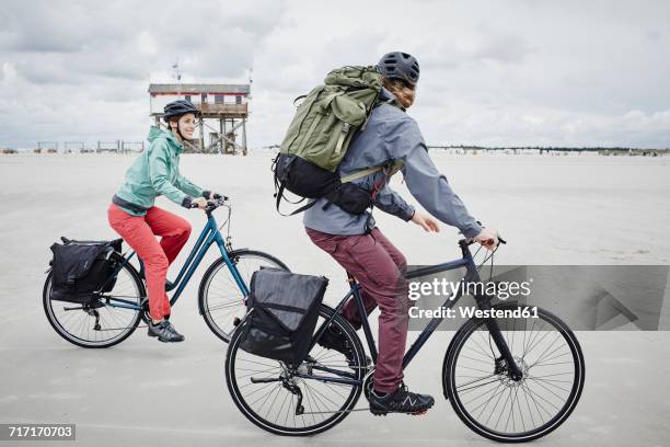 germany, schleswig-holstein, st peter-ording, couple riding bicycle on the beach - north frisia stock pictures, royalty-free photos & images