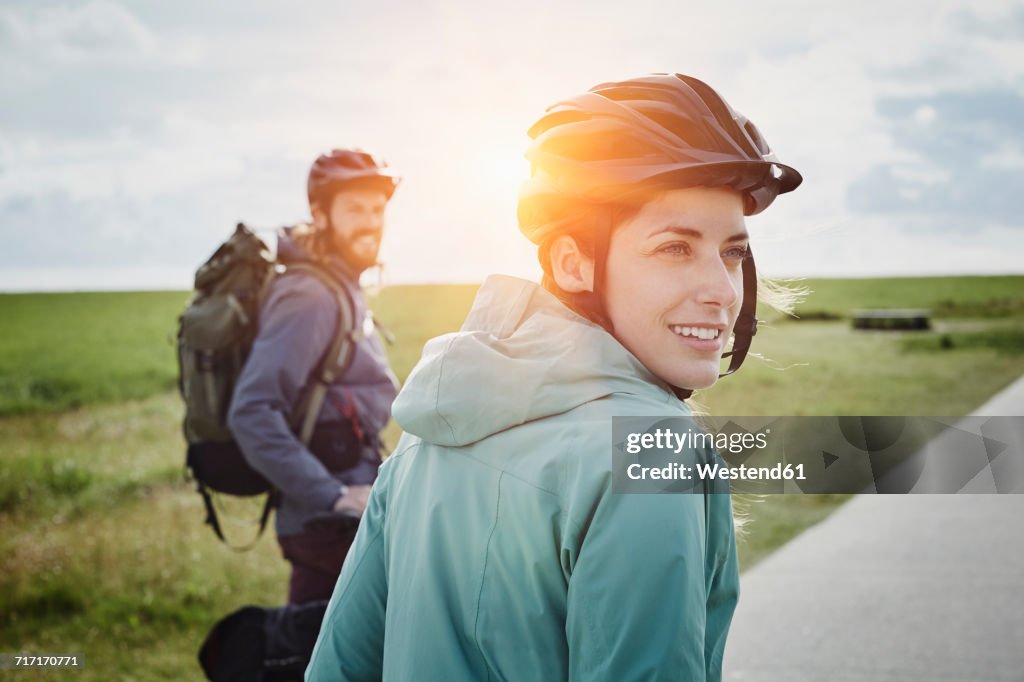 Germany, Schleswig-Holstein, Eiderstedt, couple on a bicycle tour having a break in marsh landscape