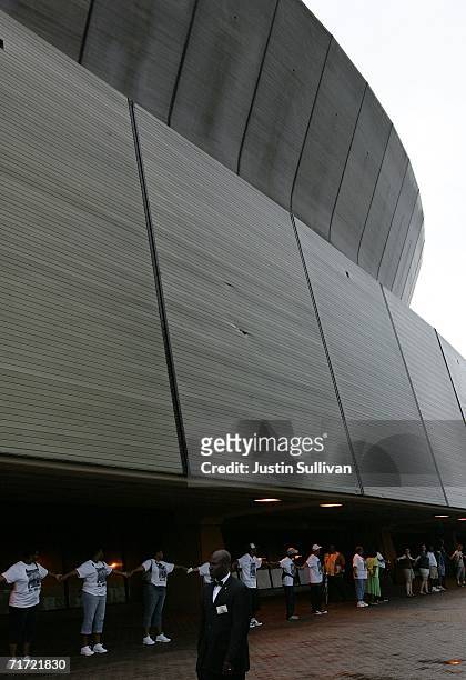 People hold hands as the create a human chain to circle the Louisiana Superdome August 26, 2006 in New Orleans, Louisiana. People held hands and...