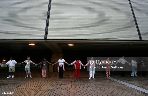 People hold hands as the create a human chain to circle the Louisiana Superdome August 26, 2006 in New Orleans, Louisiana. People held hands and...