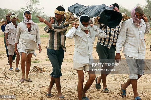 Indian villagers carry a stretcher holding the dead body of a flood victim in Kawas in Barmer District,some 400kms west of Jaipur, 27 August 2006,...