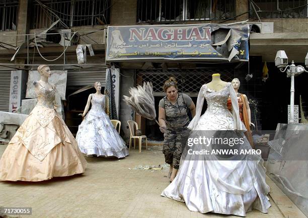 Lebanese woman removes dust from a wedding dress outside her partially destroyed shop in Beirut's southern suburb, 28 August 2006. UN Secretary...