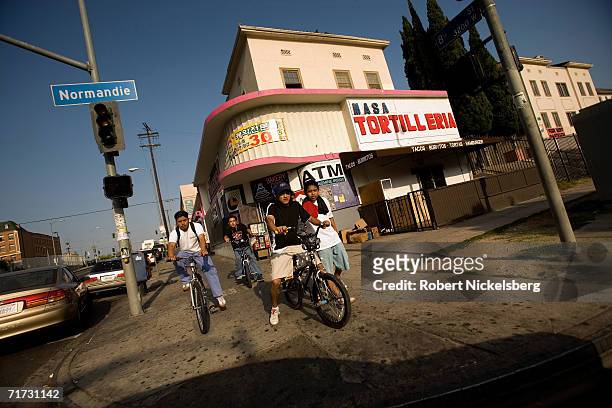 Hispanic children ride their bikes along Normandie Street and Wilshire Boulevard on August 3, 2006 in Los Angeles, California. The area was first...