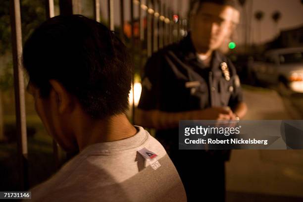 Los Angeles police officer questions one of four hispanic minors caught tagging or spray painting a wall with gang graffiti on August 3, 2006 in the...