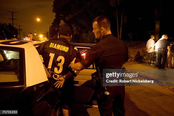 Member of the Diamond Street hispanic street gang is helped into a Los Angeles Police Department gang unit car following his arrest for drug...