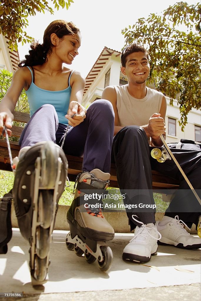 Man and woman lacing up roller blades