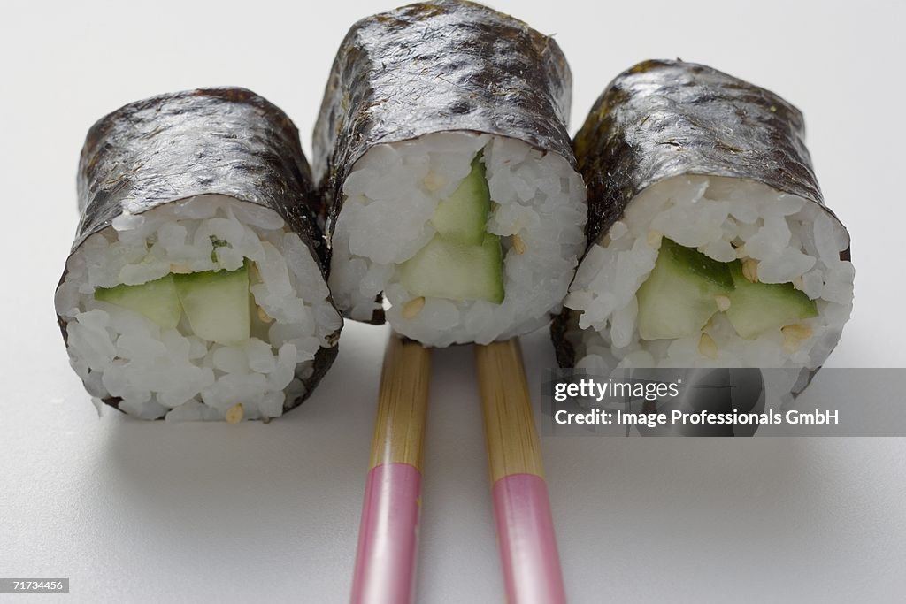 Three maki sushi with cucumber and chopsticks