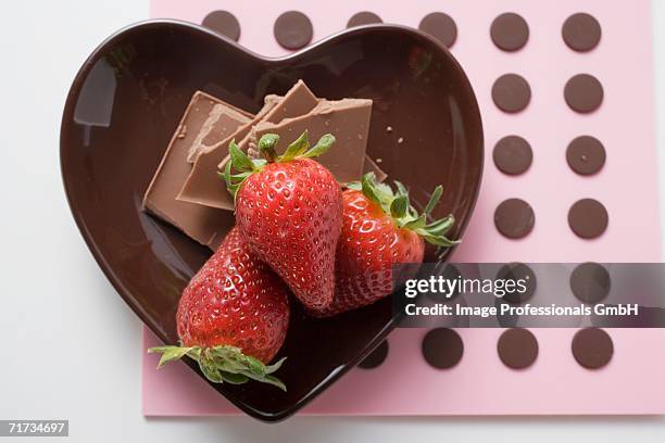 heart-shaped bowl with chocolate pieces and strawberries - chocolate covered strawberries stock-fotos und bilder