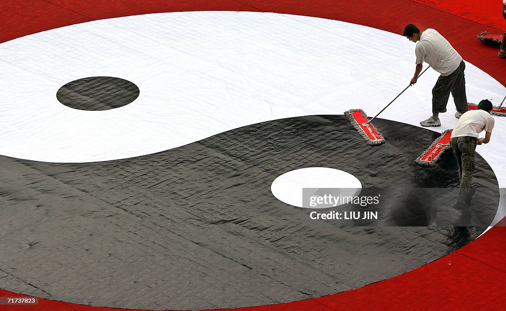 Workers clean a ying and yang symbol upo