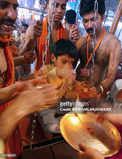Volunteers help as a young Hindu devotee seeks blessings from a priest holding the holy fire during the "Tulabharam" -- a Hindu ritual during which...