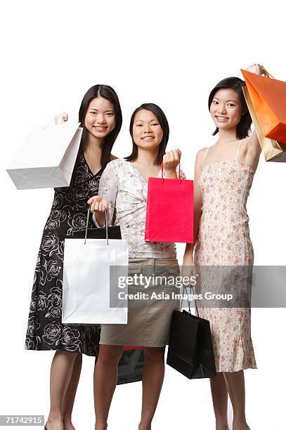 three young women carrying shopping bags - singapore shopping family stock pictures, royalty-free photos & images