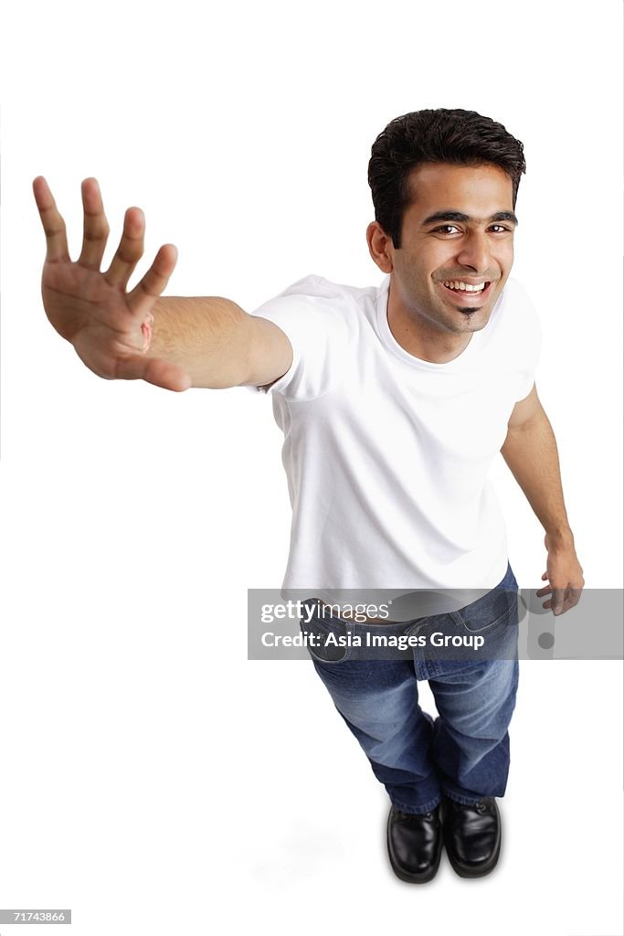 Man smiling at camera, arm outstretched, showing palm