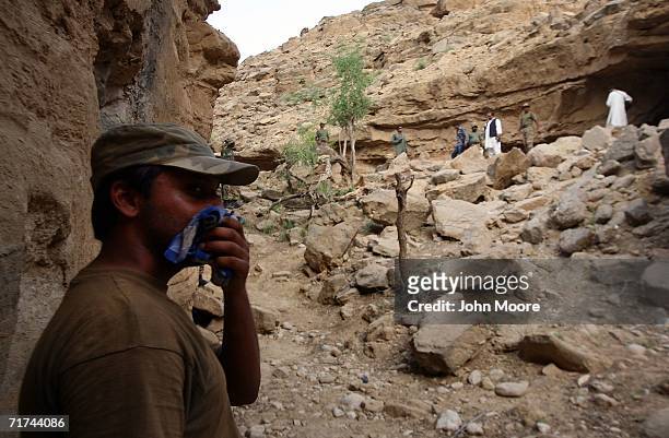 The air thick with the smell of death, a Pakistani soldier stands near the destroyed entrance to a cave where the army says that the body of Baloch...