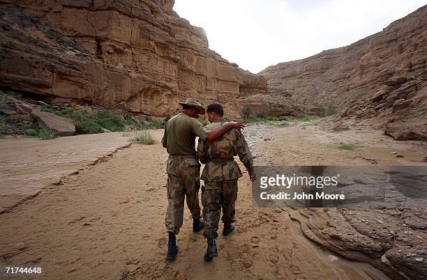 Pakistani officers congratulate each other while walking from a cave where the army says that the body of Baloch rebel leader Nawab Akbar Bugti lies...