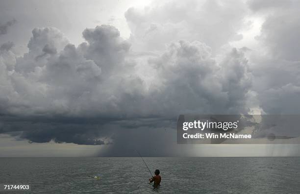 Bill Salter of Boca Raton fishes in the ocean as storm clouds from Tropical Storm Ernesto approach from the south August 29, 2006 off Captiva Island,...
