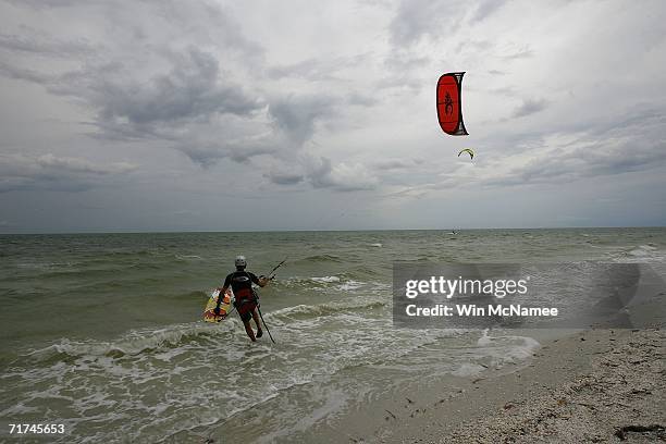 Kite-surfer wades into the ocean as storm clouds from Tropical Storm Ernesto approach from the south off Sanibel Island, Florida. Though the chance...