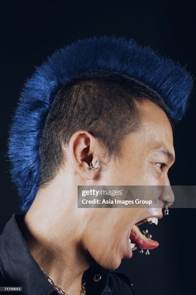 Man with mohawk, side view, mouth open, sticking tongue out