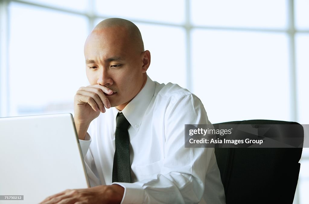 Man using laptop, hand on chin, portrait