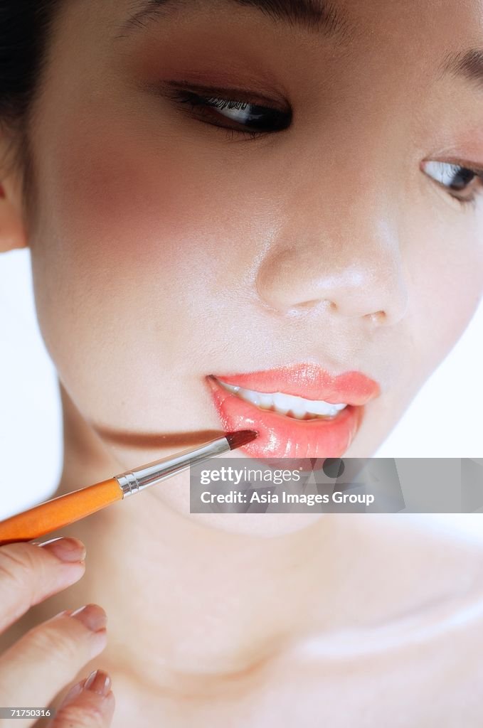 Woman applying lipstick with lip brush