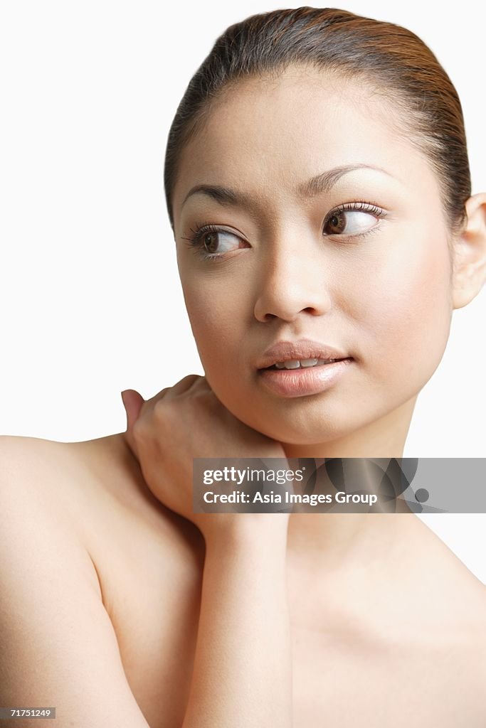 Young woman, hand around neck, looking away