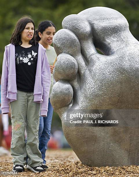 Washington, UNITED STATES: Two young girls look 30 August 2006 a the foot of "The Awakening," a five-part cast aluminum sculpture created by J....