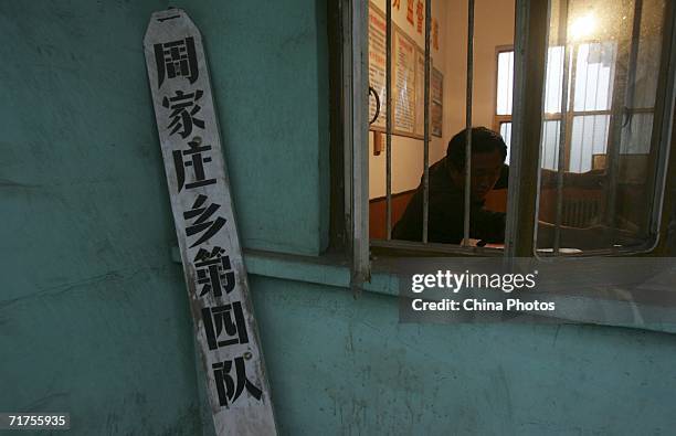Worker works at the office of the village production team, which was the basic accounting and farm production unit in the people's commune system in...