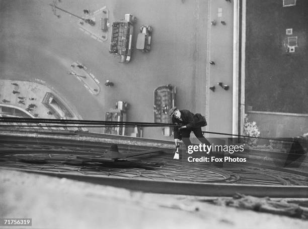 Mr Larkin lowers himself from a rope to clean the face of Big Ben, the famous clock on the Houses of Parliament, 4th March 1930.