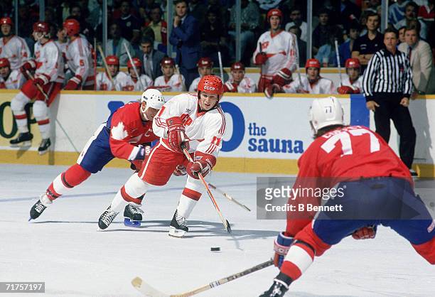 Russian professional hockey player Igor Larionov , center for CSKA Moscow and on the ice as a member of Team USSR, is checked by Canadian hockey...