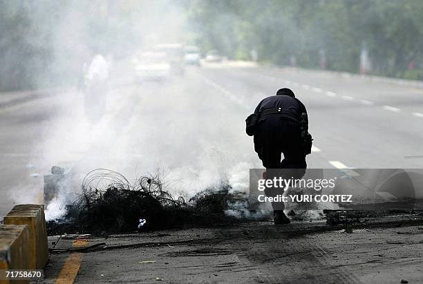 Un agente de la Policia Nacional Civil extingue el fuego de neumaticos que bloquean la carretera que une la capital y el Aeropuerto Internacional, el...