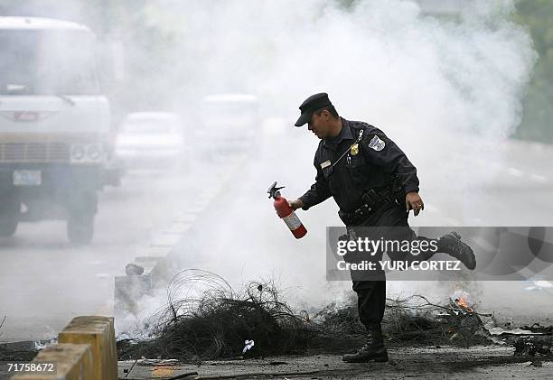 Un agente de la Policia Nacional Civil extingue el fuego de neumaticos que bloquean la carretera que une la capital y el Aeropuerto Internacional, el...