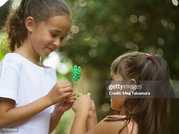 side profile of two sisters holding an artificial cloverleaf - fake of indian girls stock pictures, royalty-free photos & images