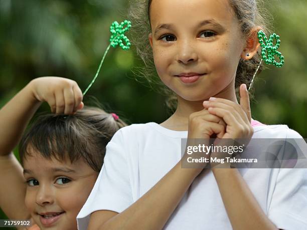 portrait of two girls holding artificial cloverleaf - fake of indian girls stock pictures, royalty-free photos & images